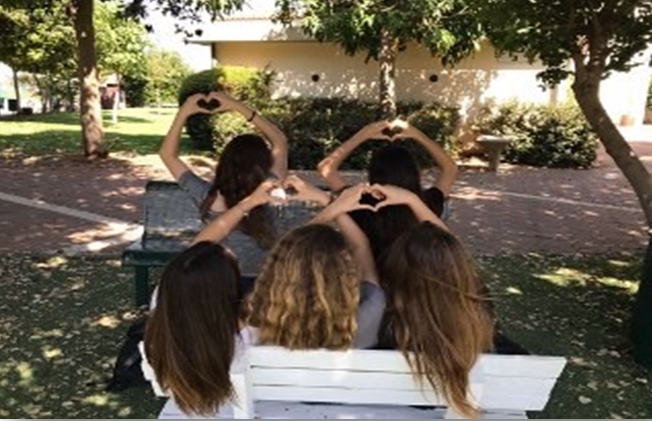 תלמידות מסמלות לב עם הידיים בבית הספר