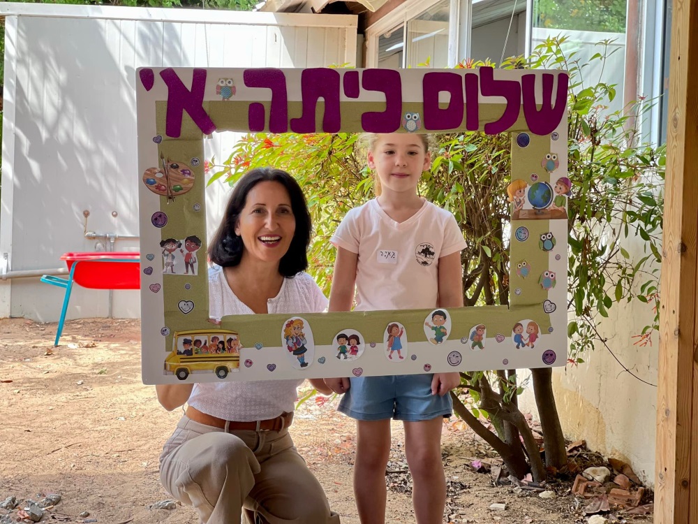 ראש המועצה אושרת גני גונן עם תלמידת כיתה א מחזיקות שלט שלום כיתה א