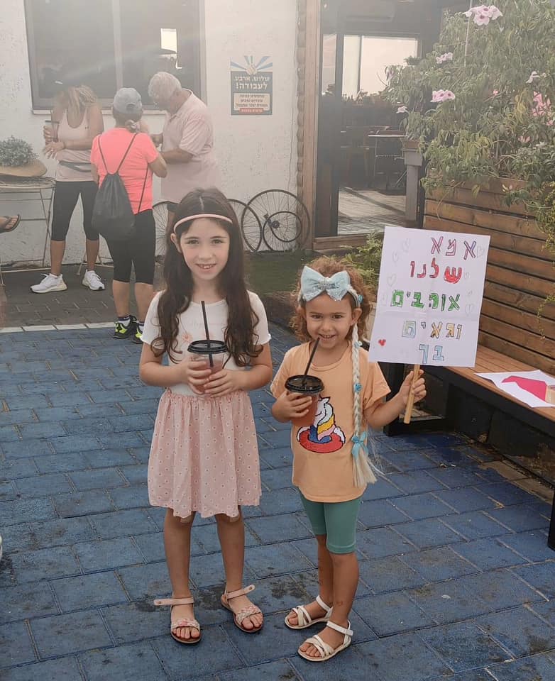 שתי ילדות מציגות שלט עידוד עם הכיתוב אמא שלנו אוהבים וגאים בך במסגרת מרוץ להעלאת מודעות לסרטן השד בדרום השרון