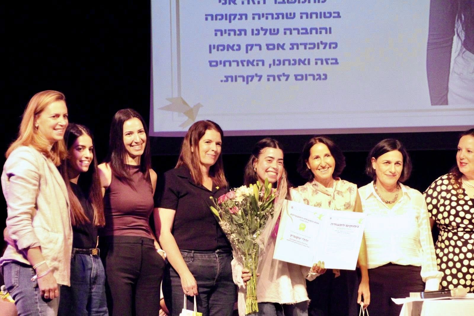 תמונה של יהלי מקבלת את תעודת הצטיינות על עשייה משמעותית ומעוררת השראה בטקס של מינהל החברה והנוער במשרד החינוך